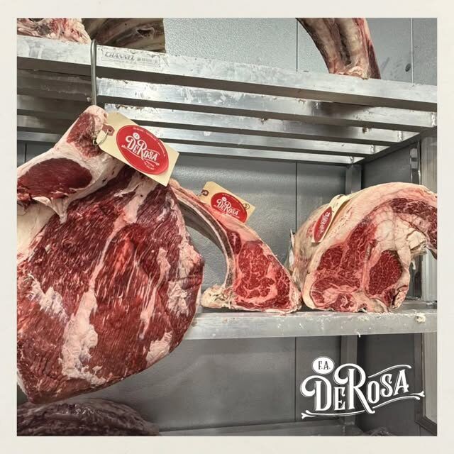 Bone-in rib primals aging on the cooler rack, each tagged by F.A. DeRosa