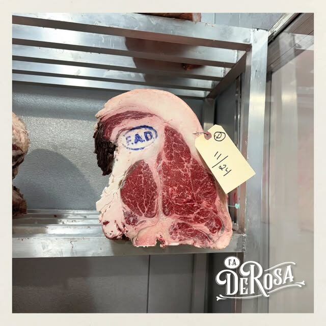 A USDA Prime primal on the cooler rack, stamped with the F.A. DeRosa brand and tagged with its aging date