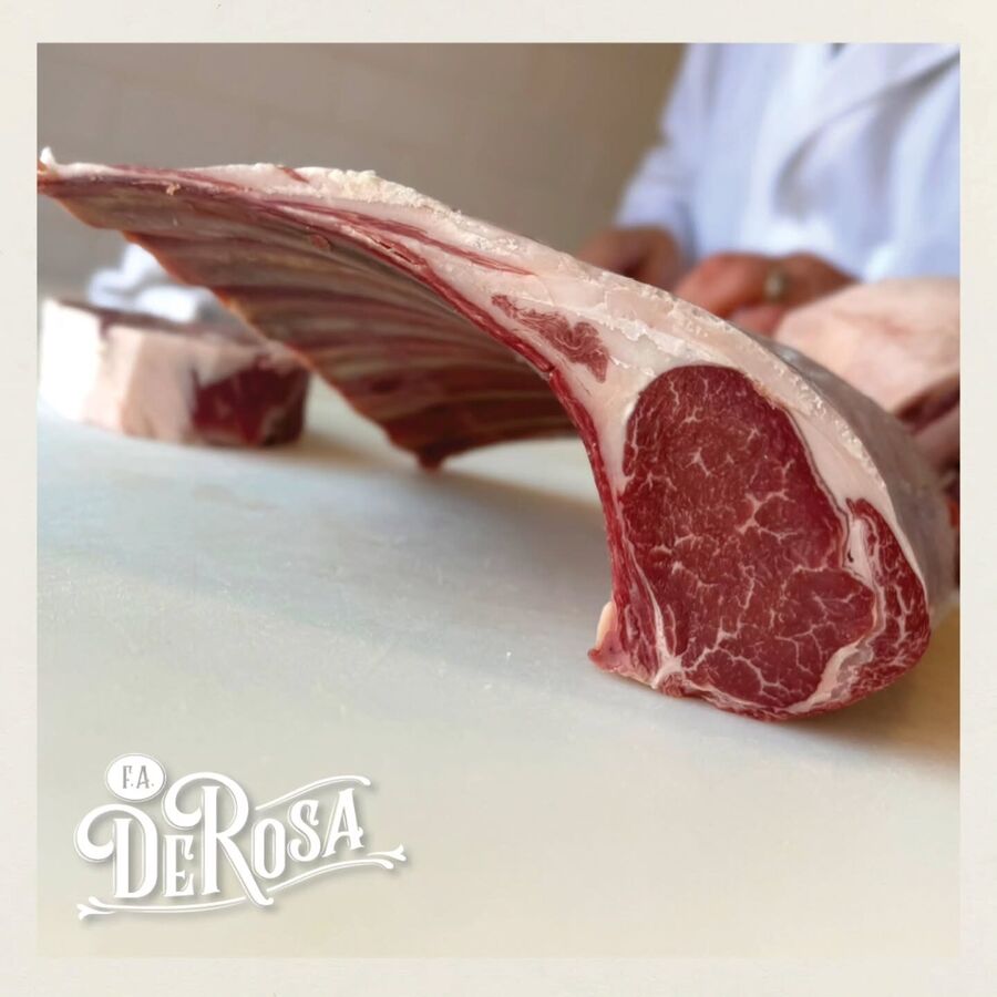 A long-bone cowboy ribeye being cut at the counter