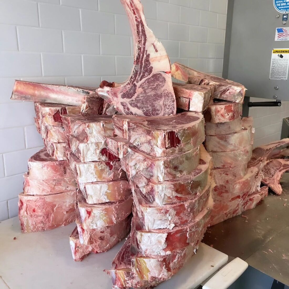 A stack of hand-cut tomahawk steaks on the butcher block